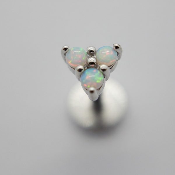 Triangular silver stud with three round opal cabochons flashing green and pink set against a soft grey background