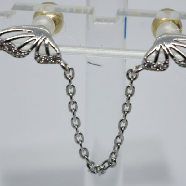 Silver butterfly-wing stud earrings with small crystals joined by a delicate chain on a clear acrylic display.