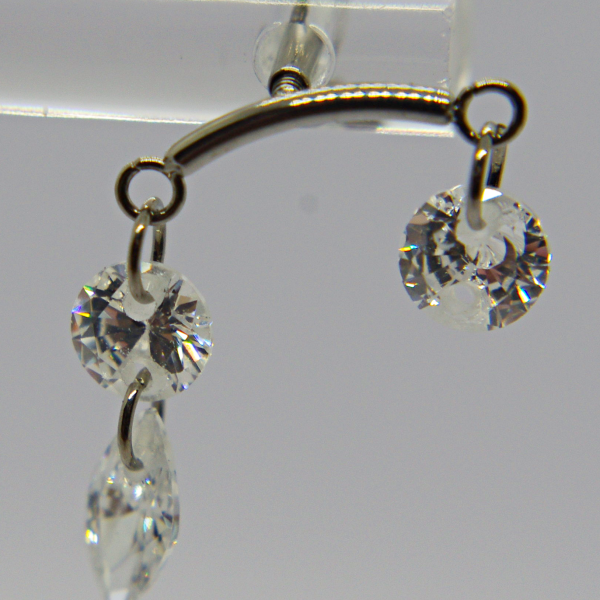 Dangling silver earring with a curved bar holding two clear faceted crystals: a round stone and a teardrop crystal.