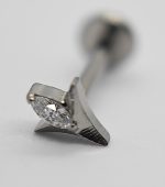 Macro view of a metal earring stud featuring a marquise-cut clear gemstone set in a triangular prong, with the post blurred in the background.
