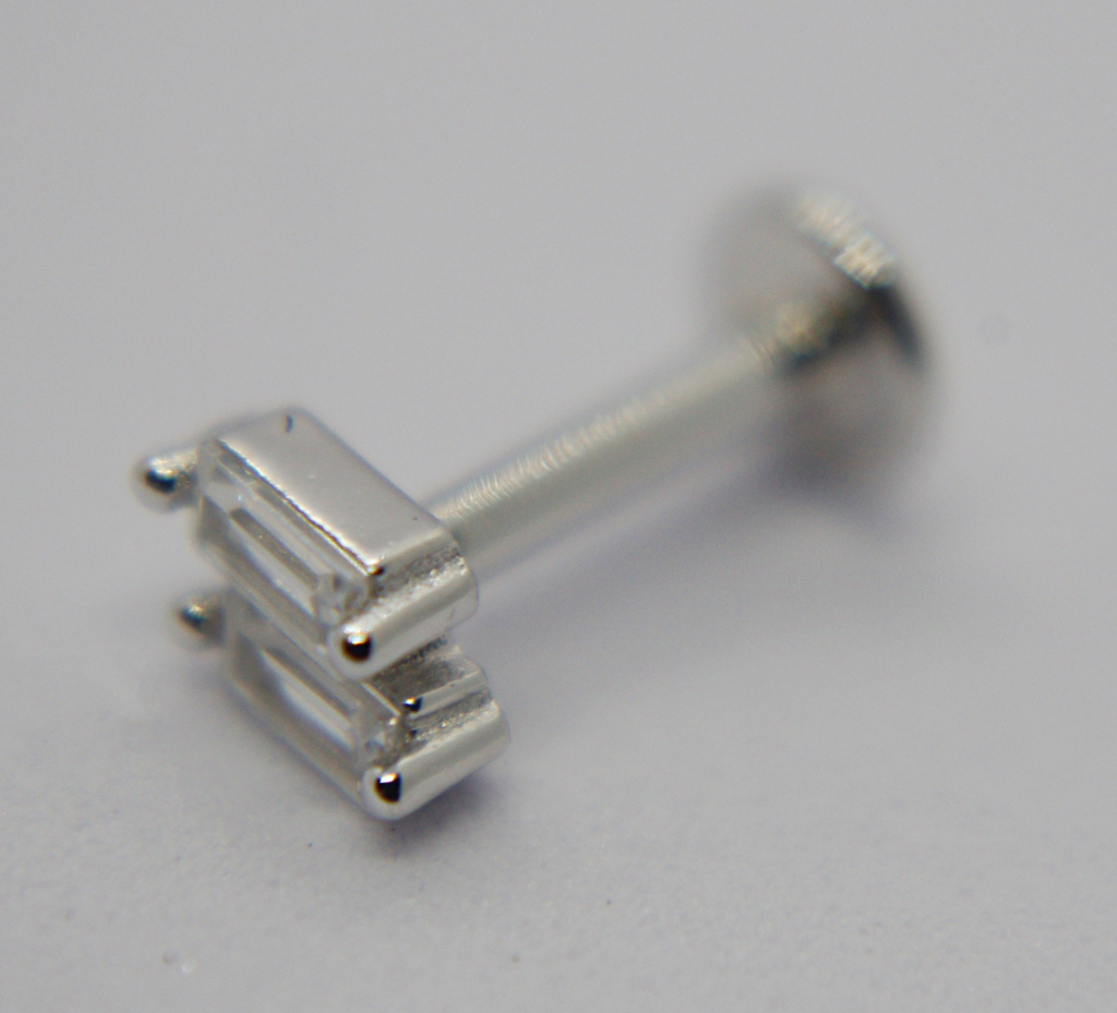 Close-up of a silver labret stud with two rectangular baguette clear stones set side-by-side on a short post and flat disc back.