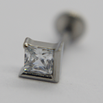 Close-up of a square-cut clear gemstone set in a silver bezel stud earring with blurred post in background.