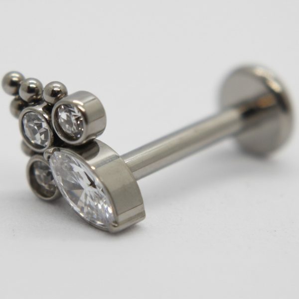 Silver labret-style earring with a large pear-shaped clear gemstone, three small round bezel-set crystals, and three tiny metal beads on white background