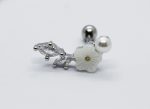 Silver ear stud with two marquise clear stones, a small white flower with gold center, and a round pearl back on white