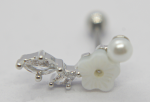 Close-up of a silver earring stud with a small pearl, a white carved flower, and two marquise clear stones.