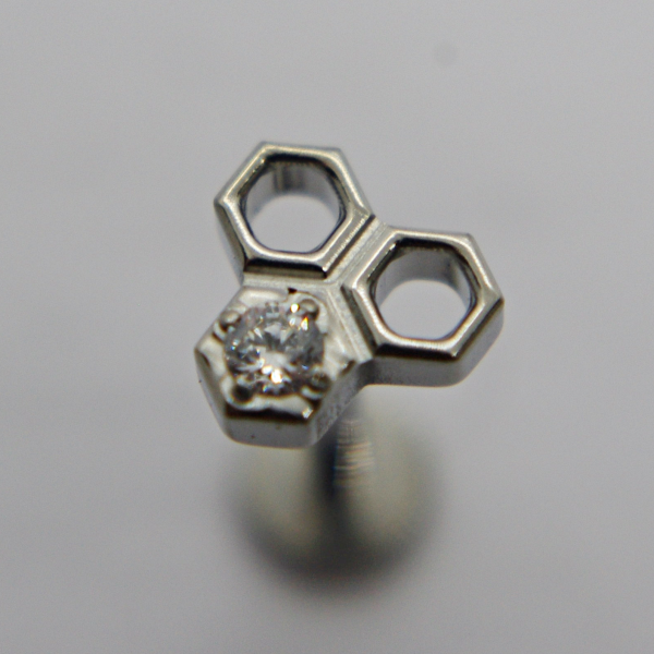 Triple hexagon silver stud with a small round clear gemstone set in one hexagon on a soft gray background.