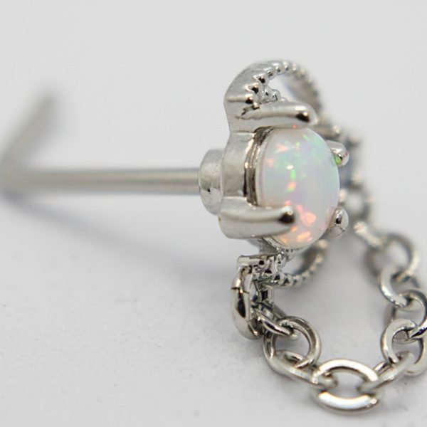 Close-up of a silver stud earring with a round opal showing green and pink flashes, attached to a short silver chain on a white background.