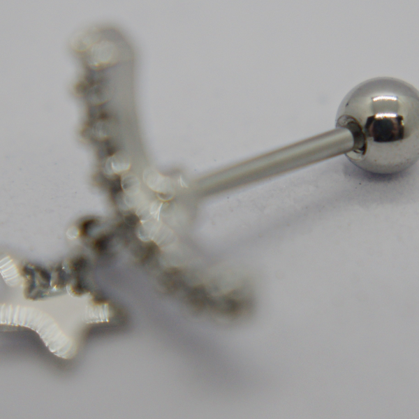 Small silver barbell earring with a shiny ball end and blurred dangling star charm on a white background.