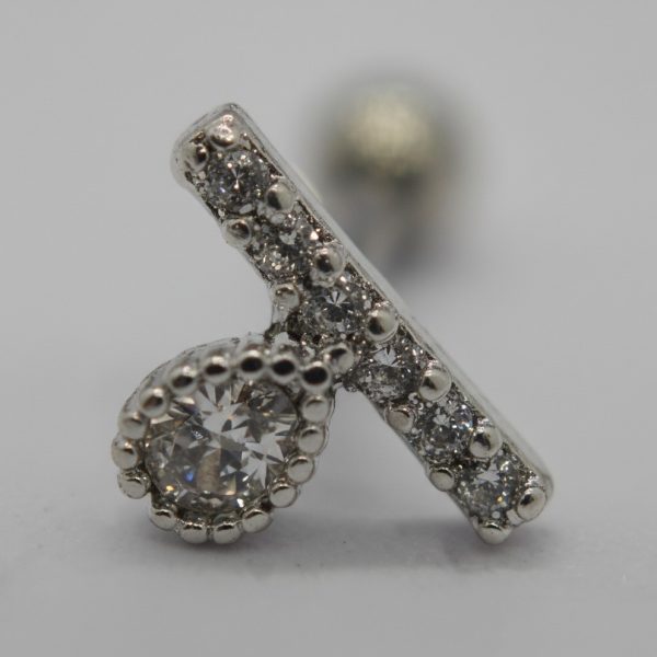 Close-up of a silver stud earring featuring a beaded-set round clear gemstone and a diagonal pavé bar of small stones