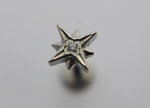 Silver three-dimensional star-shaped stud with a small central gemstone on a soft gray background.