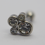 Metal stud earring with four bezel-set clear round crystals photographed in close-up on a pale background.