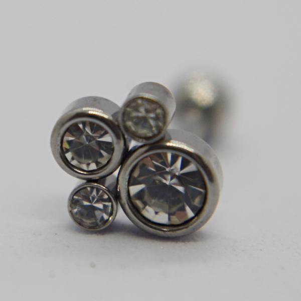 Metal stud earring with four bezel-set clear round crystals photographed in close-up on a pale background.