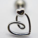 Silver metal charm showing a small solid heart attached above an open, swirled heart outline on a white background.