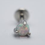 Round opal stud earring showing green and pink flashes, held in a three-prong silver setting with a blurred screw-back post.
