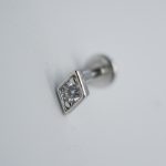 Small silver stud earring with a square bezel holding a round clear gemstone on a white background.