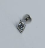 Small silver stud earring with a square bezel holding a round clear gemstone, resting on a white surface.