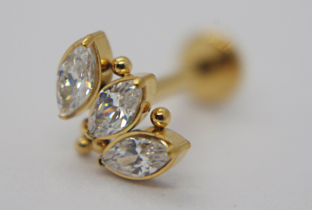 Gold stud earring with three marquise-cut clear stones set vertically and small gold bead accents.