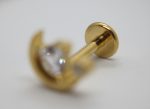 Gold metal stud with clear faceted gem, shallow focus on the round back plate and blurred gem in front.