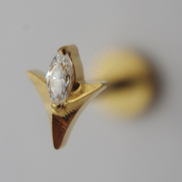 Gold stud earring shaped like a star with a marquise-cut clear gemstone, close-up on a neutral blurred background.