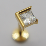 Close-up of a gold stud earring with a square princess-cut clear gemstone set in a gold bezel, angled upward.