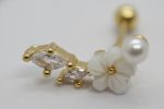 Gold ear barbell featuring two marquise clear stones, a carved white flower, and a small round pearl