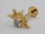 Gold labret stud with crown-like prong setting and small sparkling gemstone, shallow focus showing the gold backing.