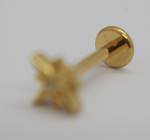 Gold stud earring on a white surface with the round back in focus and the star-shaped front blurred
