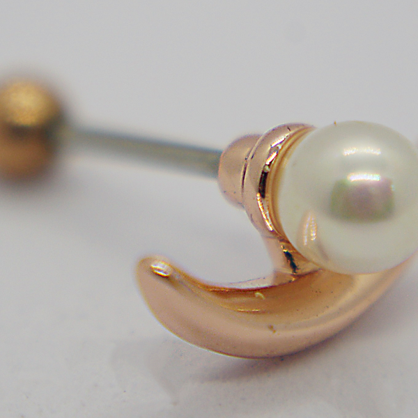 Close-up of a pearl stud earring set in a rose-gold crescent-shaped mount with a blurred metal backing.
