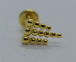 Gold stud earring with three staggered rows of small polished beads on white background, blurred backing visible.