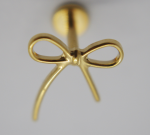Gold bow-shaped earring stud with delicate loops and tails mounted on a straight post against a pale background.