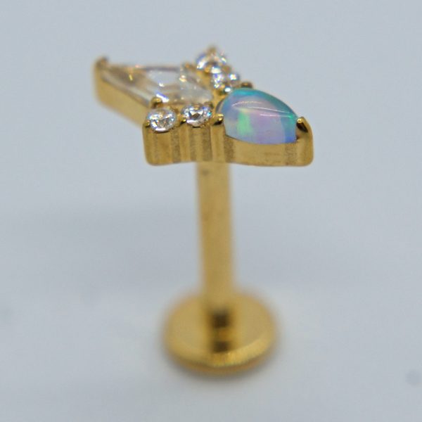Gold labret stud earring with pear-shaped opal cabochon and three small clear stones set in a gold mount on a soft white background.