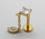 Gold labret stud with a prong-set square clear stone and a short chain holding a small rounded charm with a tiny gem