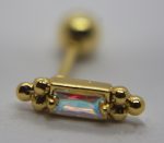 Gold barbell stud with a rectangular opalescent gem held by clustered gold beads, macro shot with blurred background.