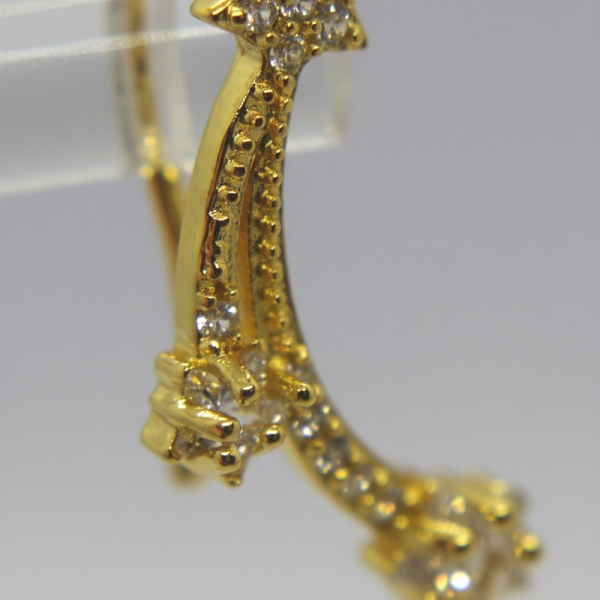 Gold earring with a star-shaped top studded with clear stones and a curved, jeweled tail ending in a small crystal cluster.