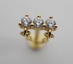 Small gold jewelry piece with three round clear stones in prong settings and tiny gold loops beneath