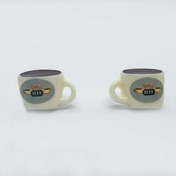 Two small cream mugs with handles on a white background, each showing an oval Central Perk logo and dark brown tops.