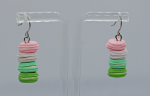 Pair of dangling earrings shaped like stacked pastel macarons — pink, white, mint and green — hanging on a display stand.