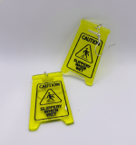 Two neon yellow miniature Caution Slippery When Wet sign earrings with black graphics and silver hooks on white background