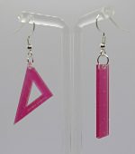 Translucent pink acrylic ruler earrings, one triangular and one rectangular, hanging from silver hooks on a clear stand.