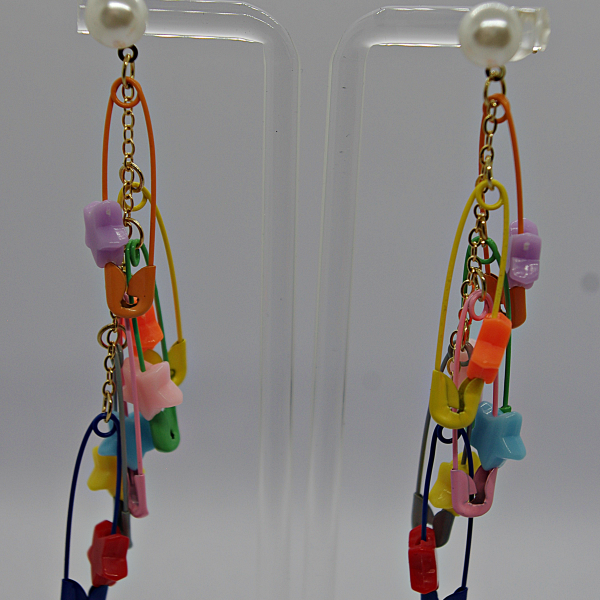 Long dangly earrings with pearl studs, gold chains and multicolored plastic charms (stars, clips, safety-pin shapes).