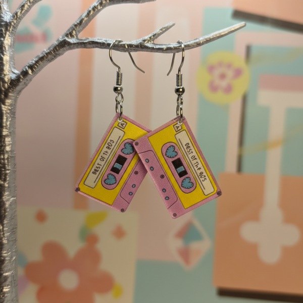Pink-yellow cassette earrings labeled Best of the 80s hang from a silver tree against a pastel backdrop.