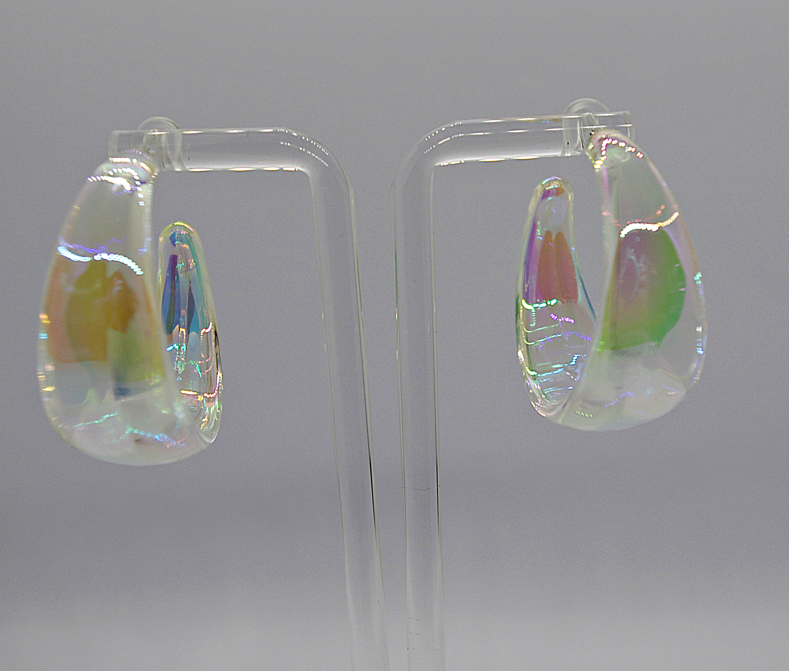 Pair of translucent iridescent teardrop glass earrings displayed on a clear acrylic stand.