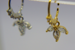 Gold hoop nose ring with three marquise-cut clear stones arranged like a small flower, with a blurred silver earring in the background