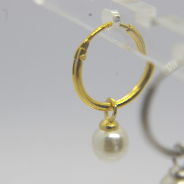 Gold hoop earring with small dangling white pearl, photographed on a clear display with a blurred matching hoop behind.