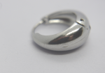 Close-up of a small polished silver crescent hoop earring with a hinge and light surface scratches on white paper.
