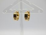 Small gold hoop earrings with single clear stone inset, hanging on a clear plastic display against a pale gray background.