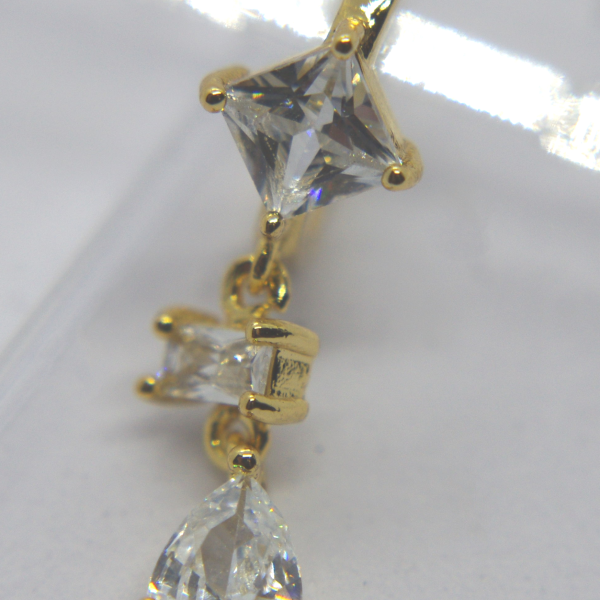 Gold dangling earring with three clear faceted stones: a square top, a small rectangular middle and a pear-shaped drop.