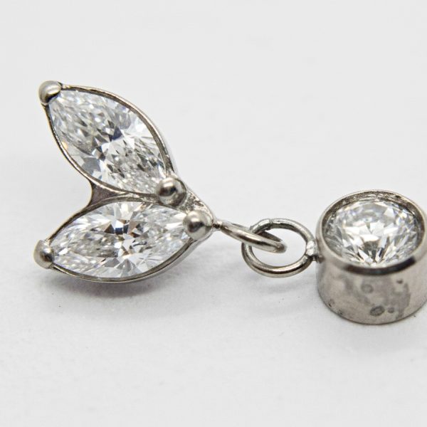 Silver pendant with two marquise-cut diamonds arranged like leaves and a round bezel-set diamond linked by a small ring.