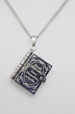 Silver book locket pendant engraved For all those who found themselves in books, hanging from a silver chain on a plain white background.