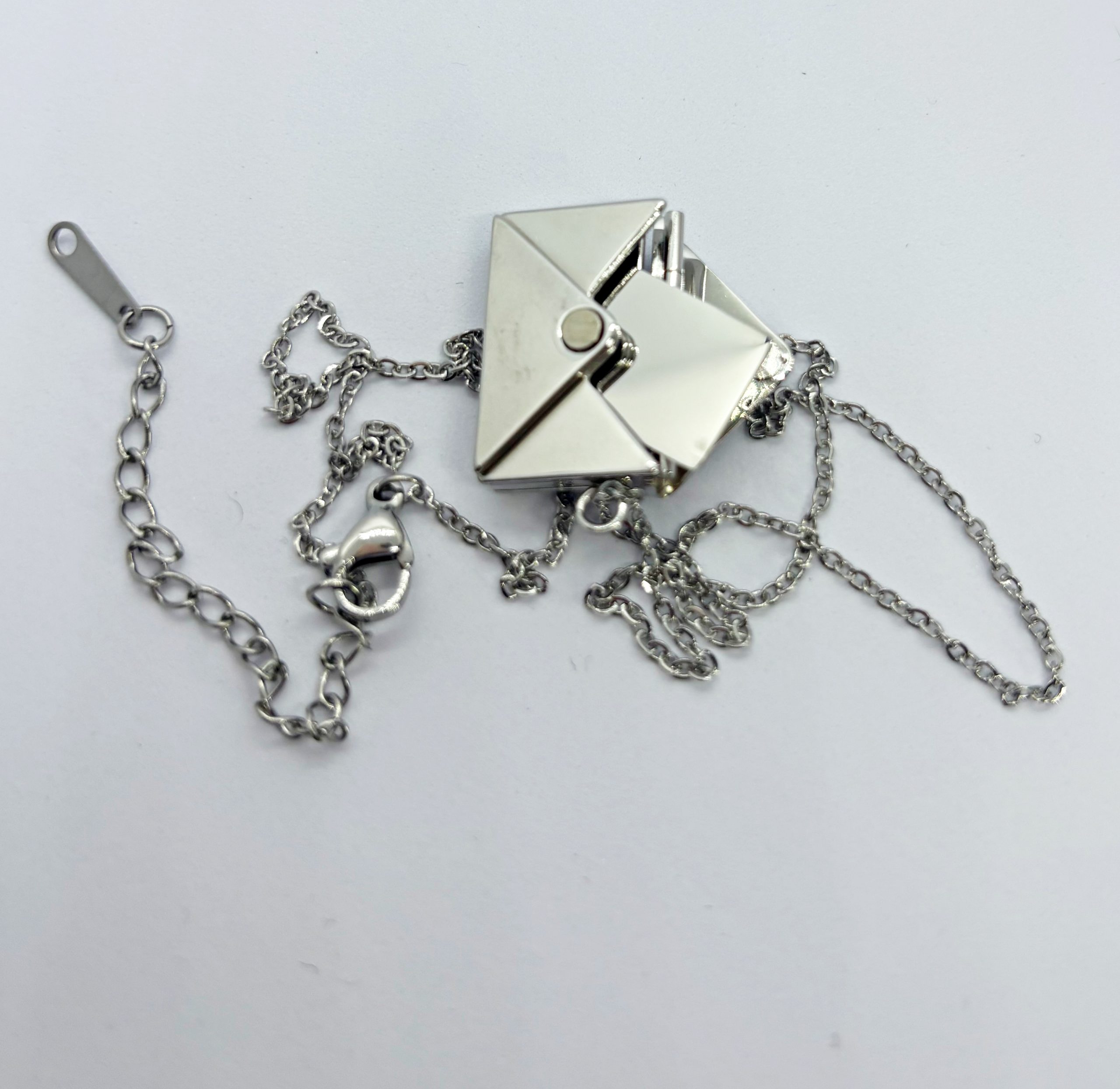 Silver origami-style geometric pendant necklace with tangled fine chains and lobster clasp on a white background.